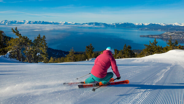Female skier carves down Crystal Ridge with panoramic views of Lake Tahoe at Diamond Peak, Nevada.