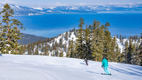Skier carves on freshly groomed corduroy with a bluebird sky above Lake Tahoe at Heavenly Mountain Resort.