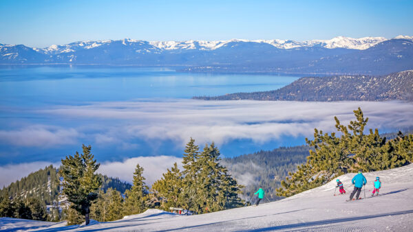 Family skiing together down Crystal Ridge with Lake Tahoe in the distance at Diamond Peak Ski Resort, Nevada.