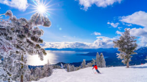 Skier descends a sunlit slope at Diamond Peak Ski Resort with panoramic views of Lake Tahoe, Nevada.