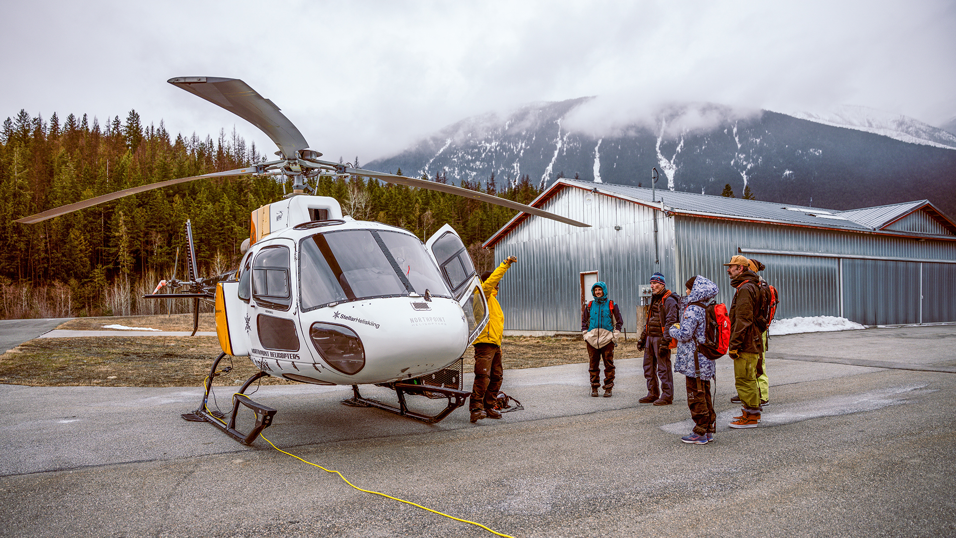 Skiers getting briefed in front of helicopter before going heli skiing
